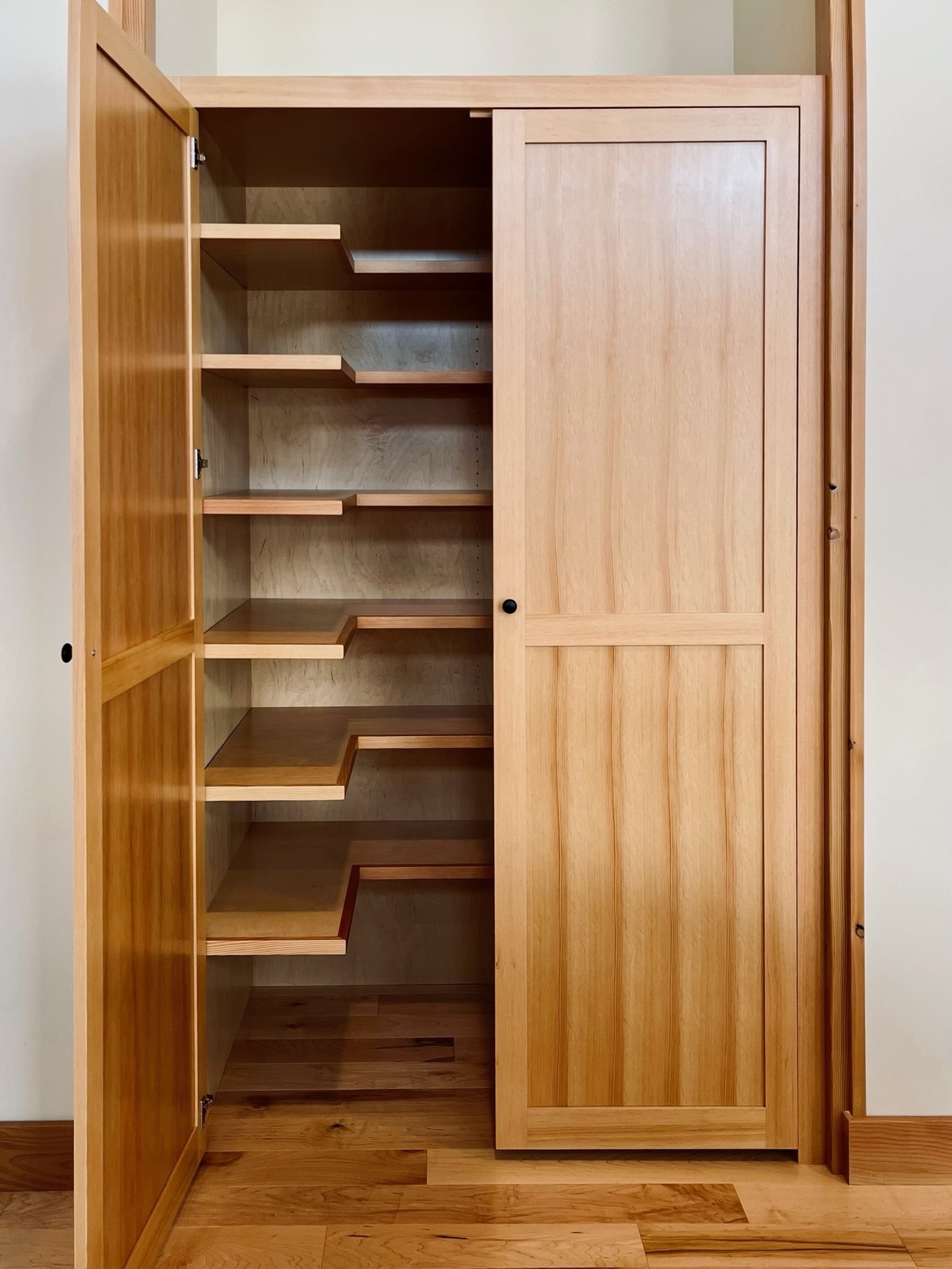 Custom floor-to-ceiling pantry with hardwood doors built by Willow Woodcraft