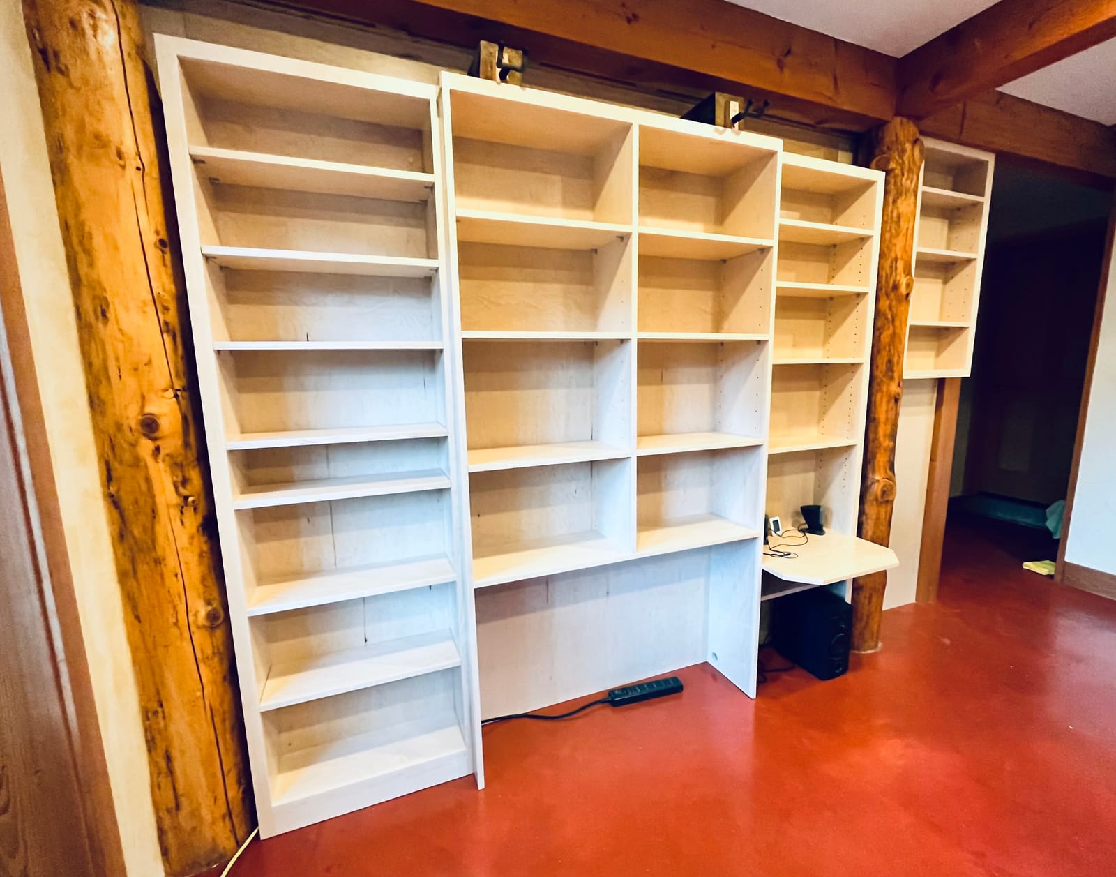 Custom floor-to-ceiling built-in bookcase fitted between two live-edge wood posts by Willow Woodcraft